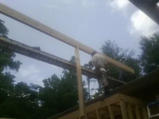 Carpenter setting a ridge beam over a new addition frame — Ice Dam Removal by Roofing Brothers in Henry