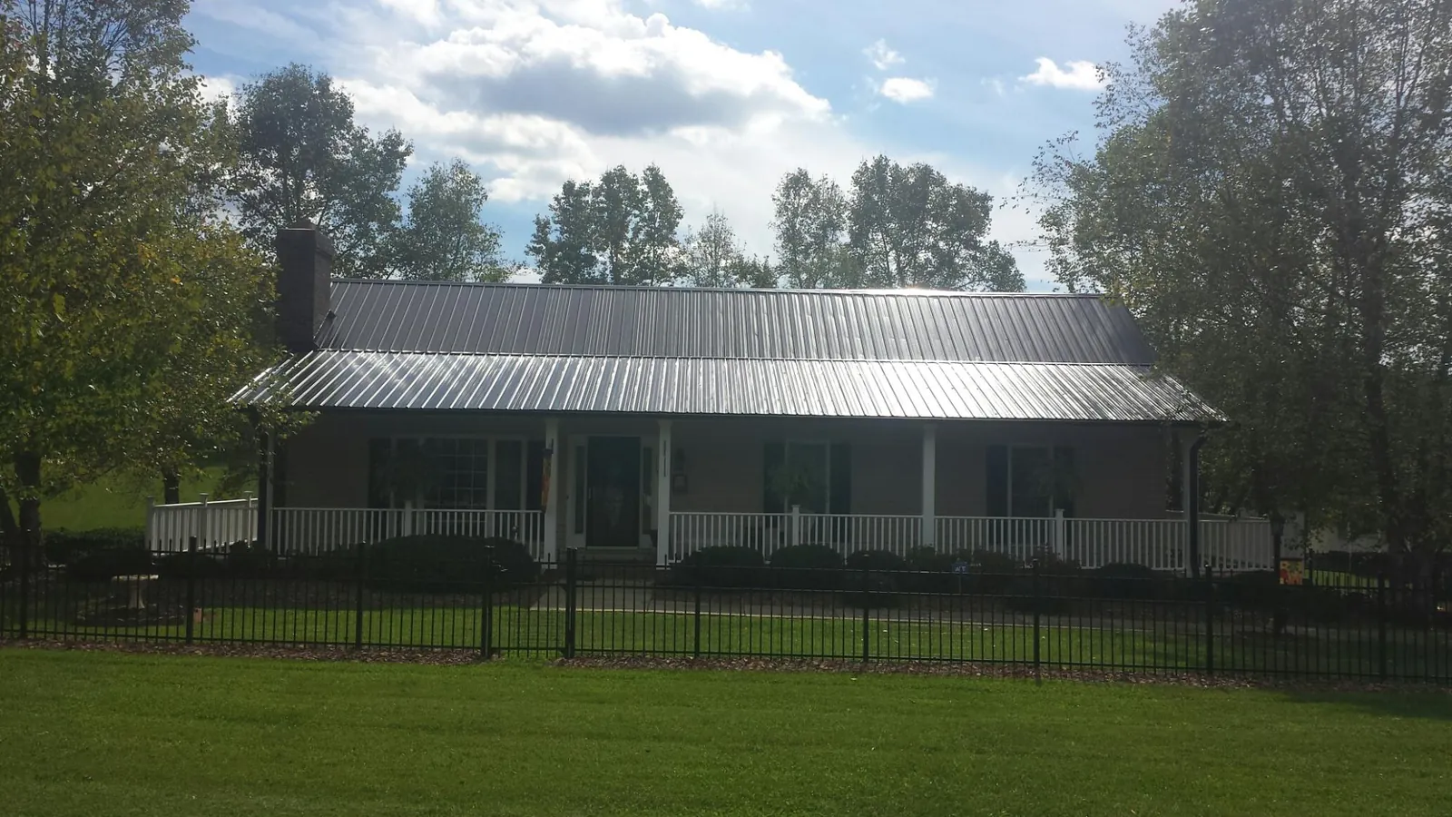 Gray metal roof on a brick ranch with a full width front porch — Gutter Guard Installation work by our crew in Henry