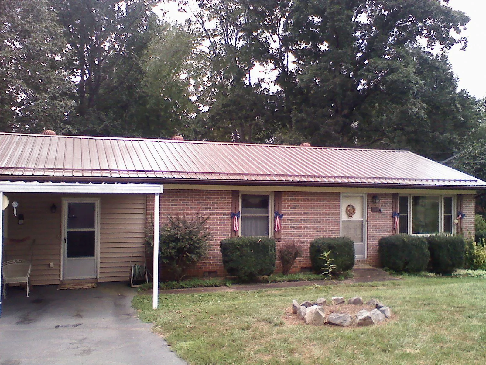 Bronze metal roof and carport on a brick ranch home — Roof Repair work by our crew in Henry